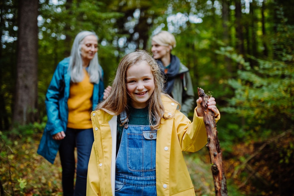 Une petite fille joyeuse lors d'une promenade dans la forêt avec sa mère et sa grand-mère.