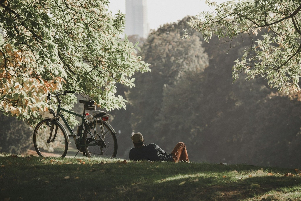Un uomo giace su un prato accanto alla sua bicicletta nel parco.